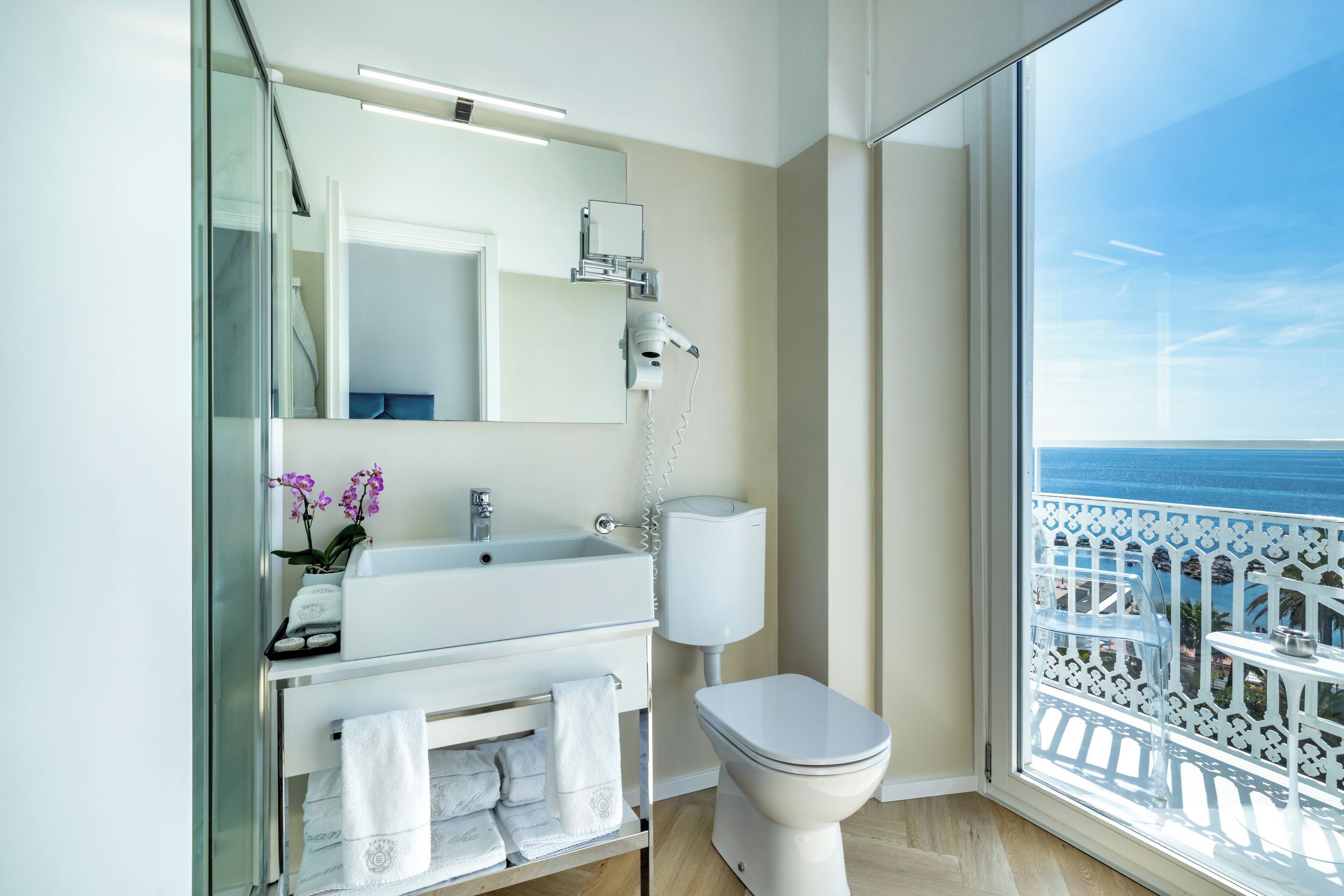 A modern bathroom with a sink, toilet, and a large mirror.