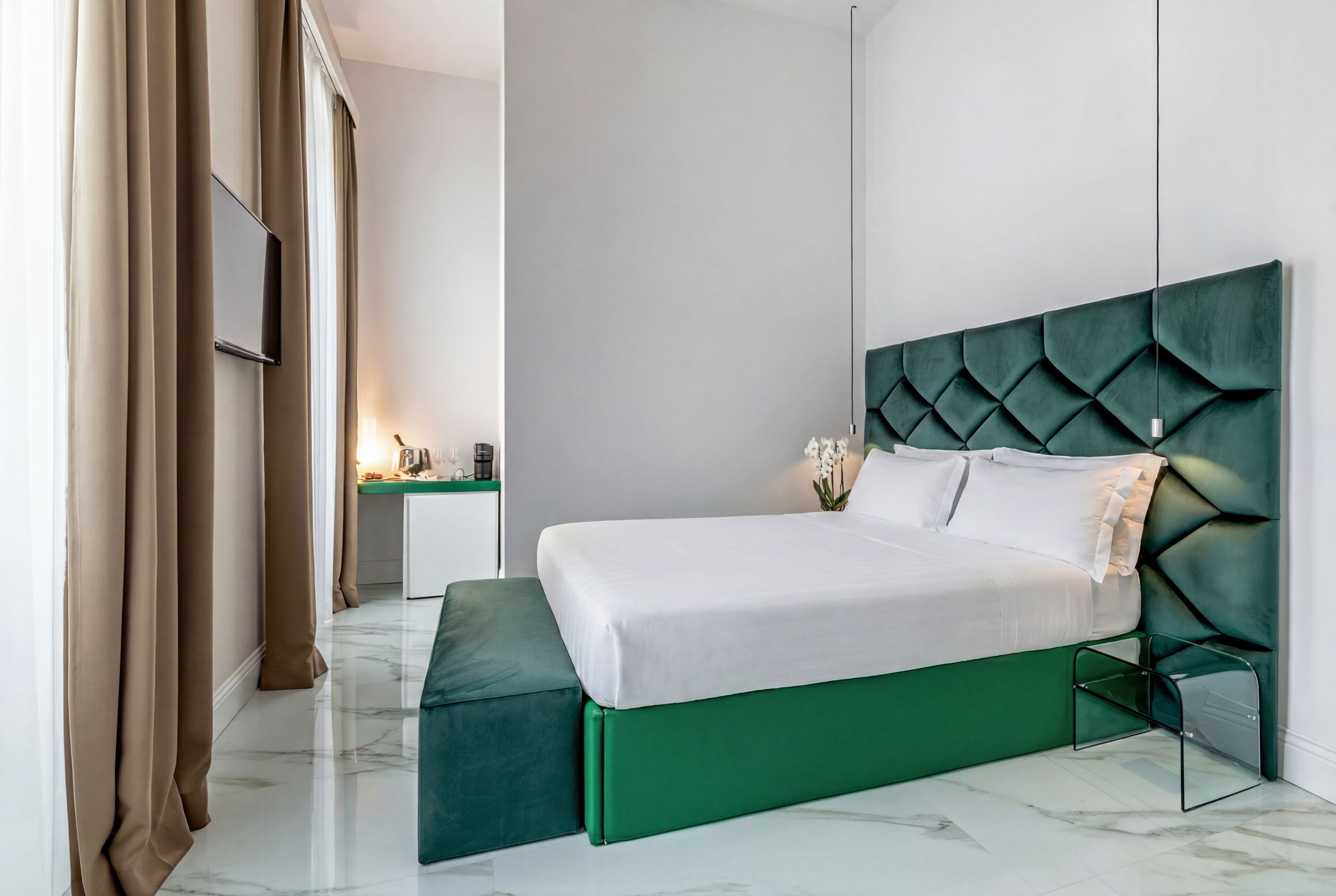 Een moderne hotelkamer met een met groen bekleden bed, een flatscreen televisie, een nachtkastje en een groene bank.
