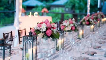 A long table set for a formal event with floral centerpieces, candles, and clear glassware.