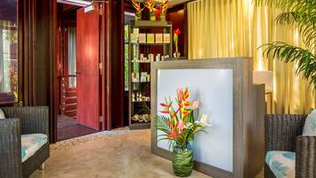 A reception area with wicker furniture, a reception desk, and a display of toiletries.