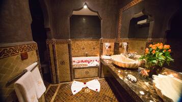 Un baño con bañera, dos lavamanos, un espejo y un lazo decorativo en el suelo.