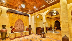Eine geräumige Lobby mit aufwendigen Fliesenböden, einem großen dekorativen Bogen und einer Springbrunnen.