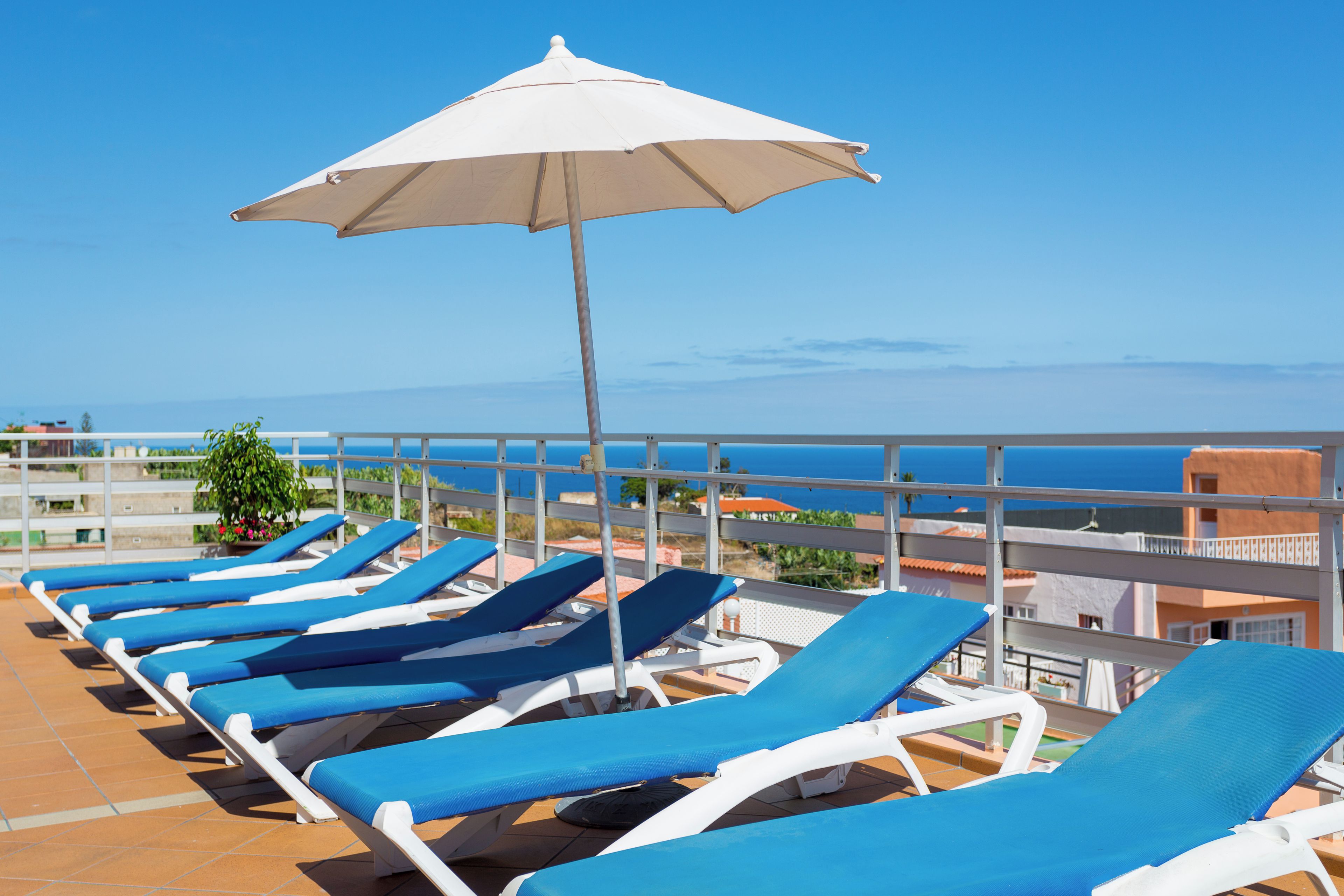 A terrace with sun loungers and a beach umbrella.