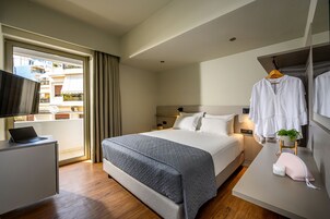 Una habitación de hotel moderna con cama, mesita de noche y televisor sobre un escritorio.