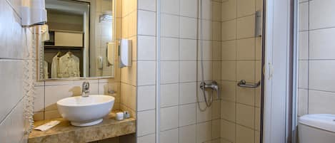 A bathroom with a sink, mirror, towel rack, and shower.