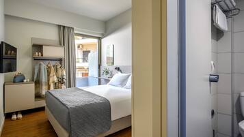 A hotel room with a bed, a wardrobe, a bathroom, and a view of the outside balcony.
