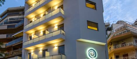 Un hotel de varios pisos con balcones, un letrero de neón y una entrada visible.