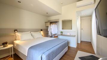 A modern hotel room with a large bed, bedside table, and a laptop on a desk.