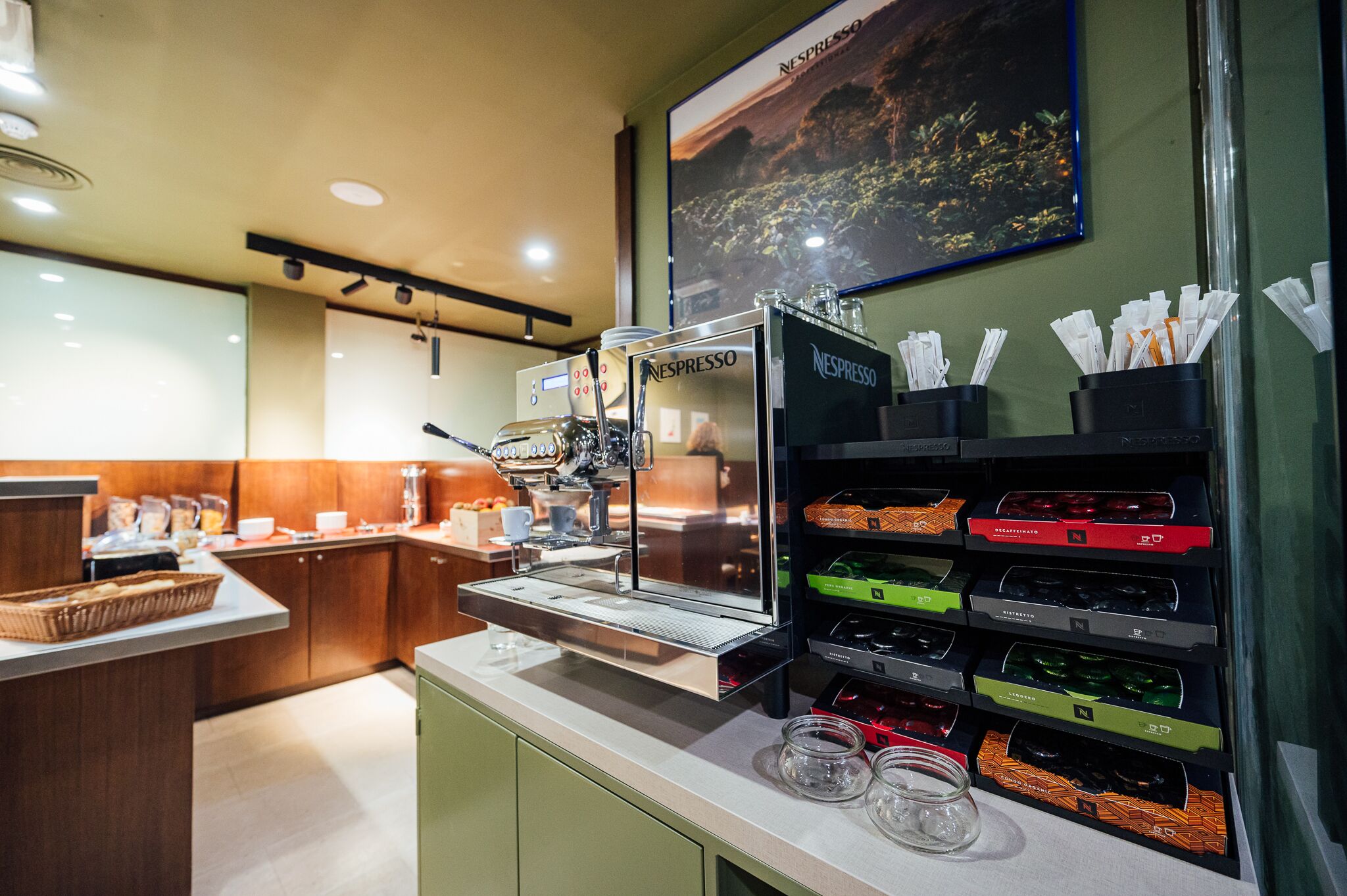 A coffee station with a Nespresso machine, a variety of coffee pods, and a basket on the counter.