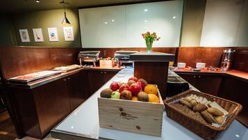 A buffet area with a variety of fruits and bread.