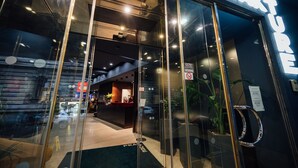 La entrada de un hotel con fachada de vidrio, una recepción y un letrero que dice "PEAK TURE".