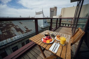 A wooden table with breakfast items on a balcony overlooking a cityscape. - PeakTure Hotel Bucharest (Bucharest)