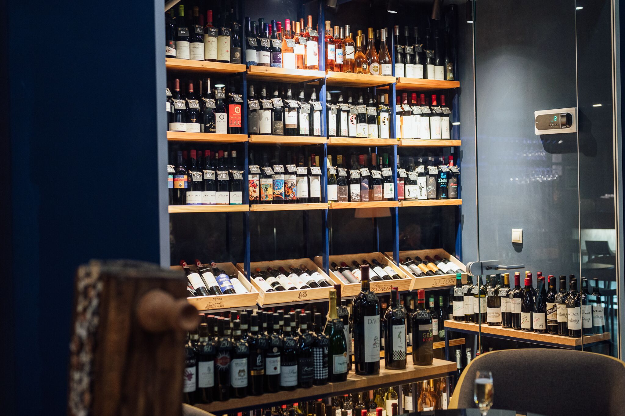 A wine cellar with shelves of wine bottles and a wooden counter with more bottles.
