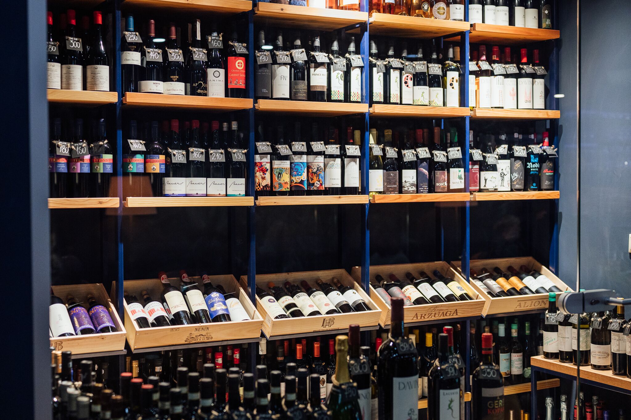 A wine store with multiple shelves and wooden crates filled with various wine bottles.