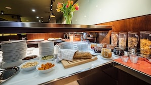Montaje de bufé con diversos alimentos, como frutas, nueces y pan, dispuestos en una barra.