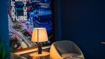 A modern room with a cityscape poster, a lamp on a wooden stump, and a curved chair.