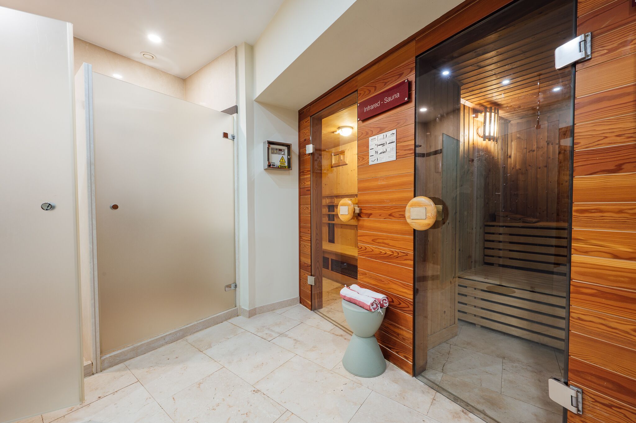 A bathroom with a wooden sauna door, a toilet, and a shower area.