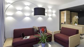 Una sala de estar moderna con un sofá, una mesa de centro, una computadora portátil y una lámpara.