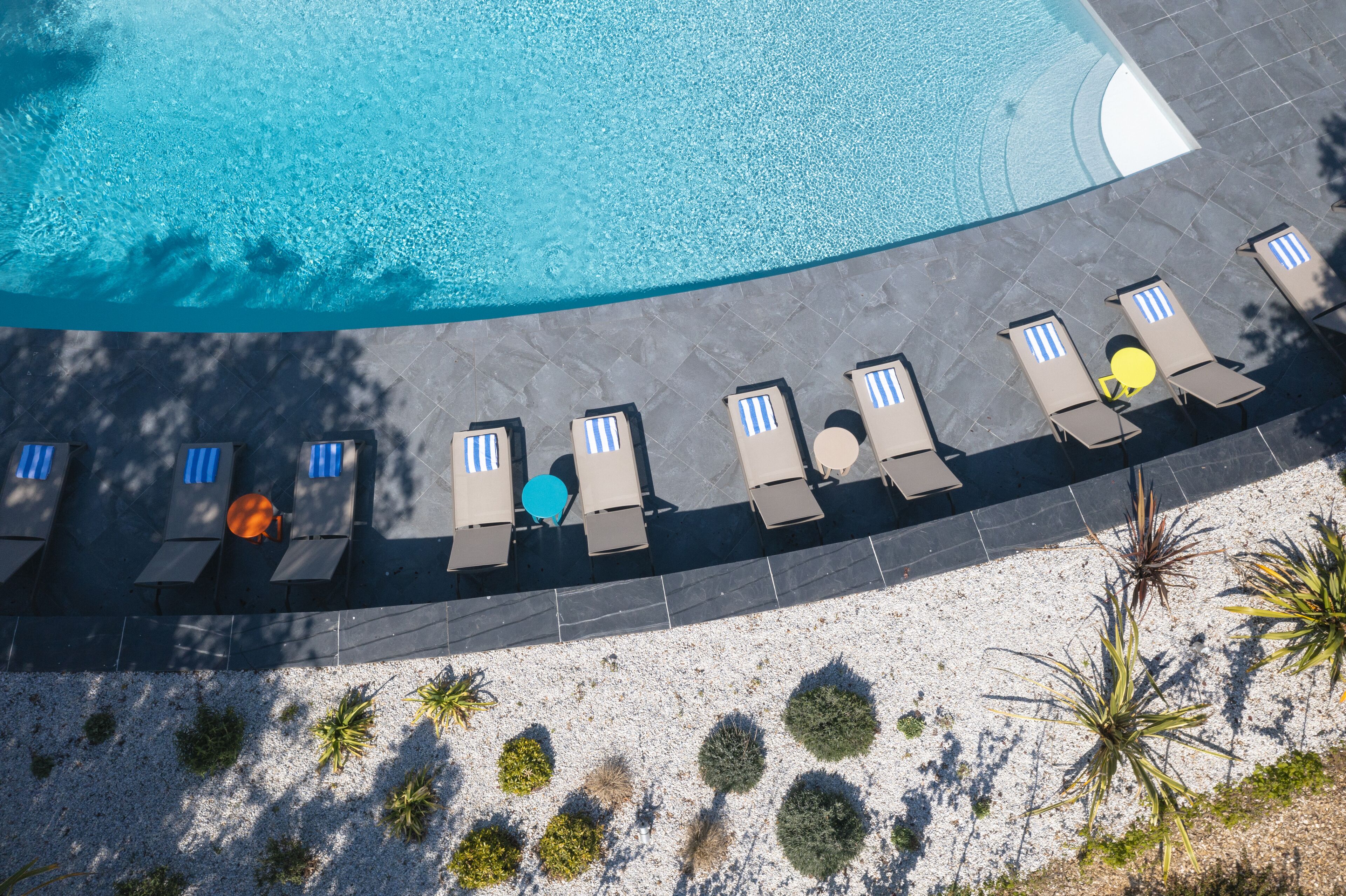 A rooftop pool with lounge chairs and small plants.