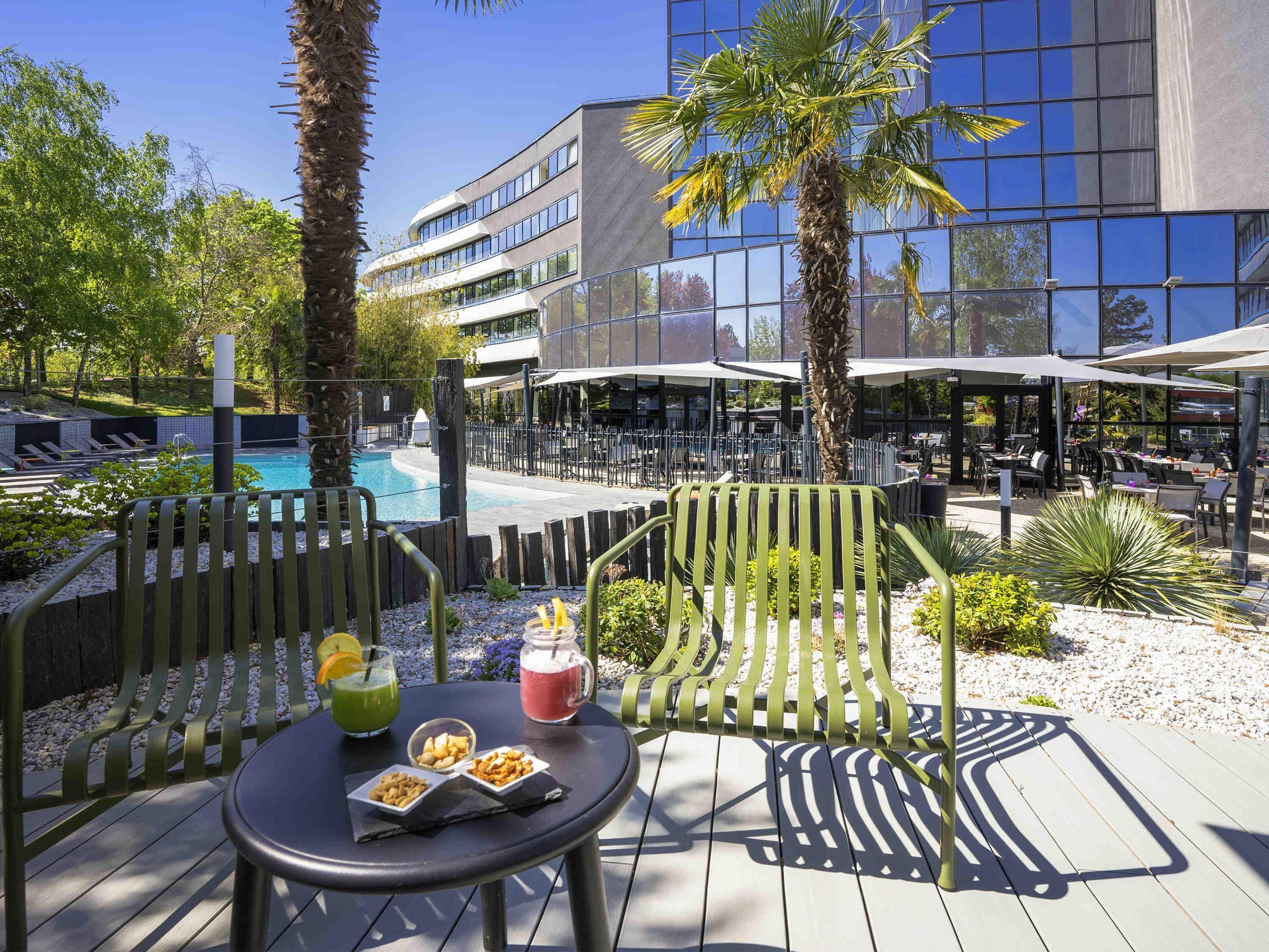 A poolside area with outdoor seating, a pool, and a modern building with large windows.