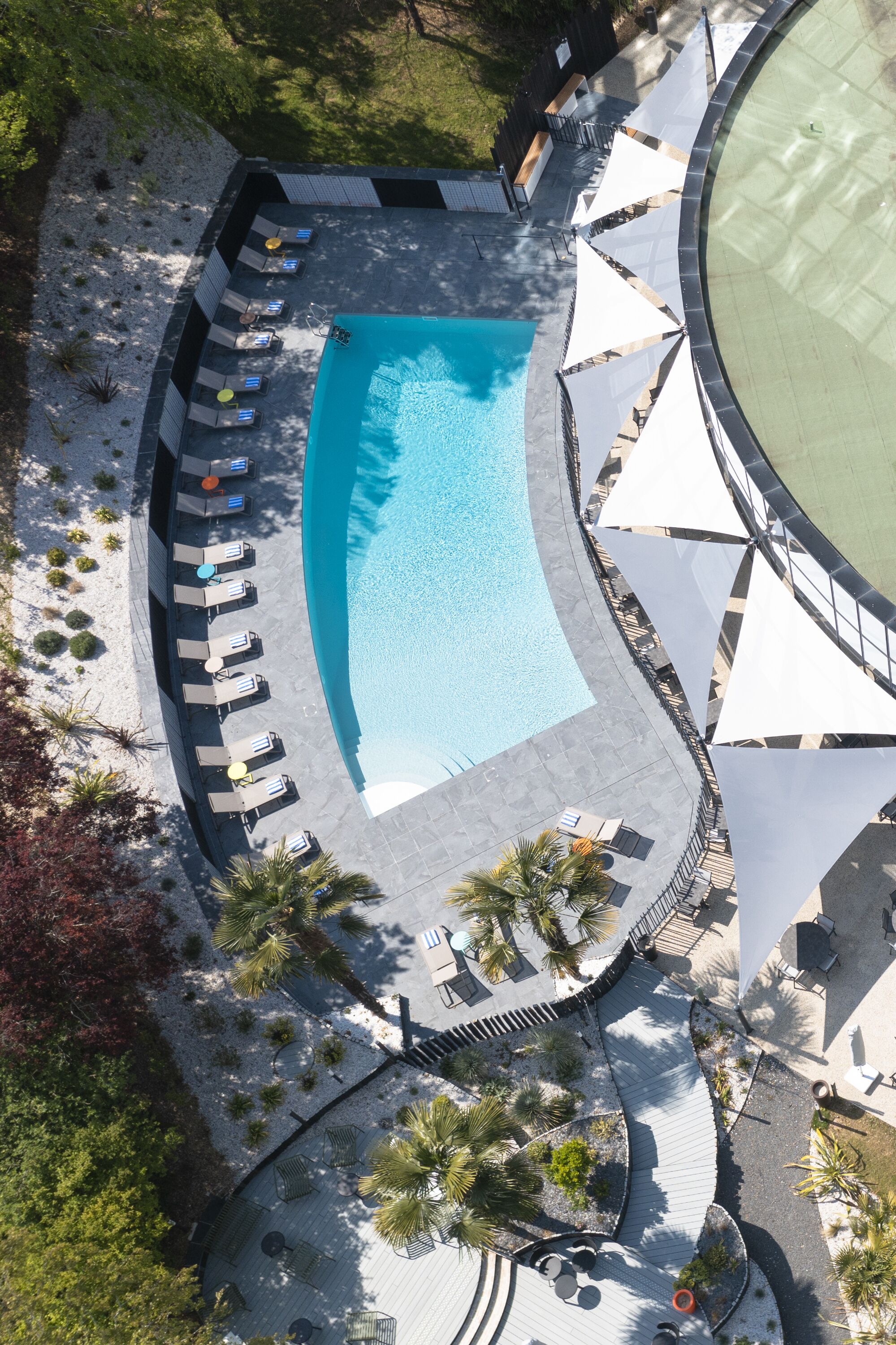 An aerial view of a swimming pool area with lounge chairs and umbrellas.