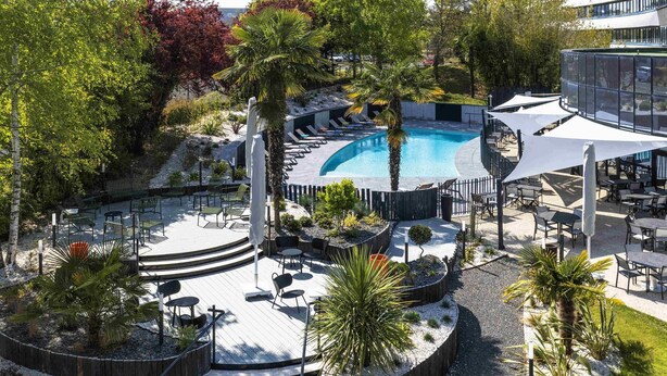 A pool area with a circular design, outdoor seating, and a staircase leading to a deck.