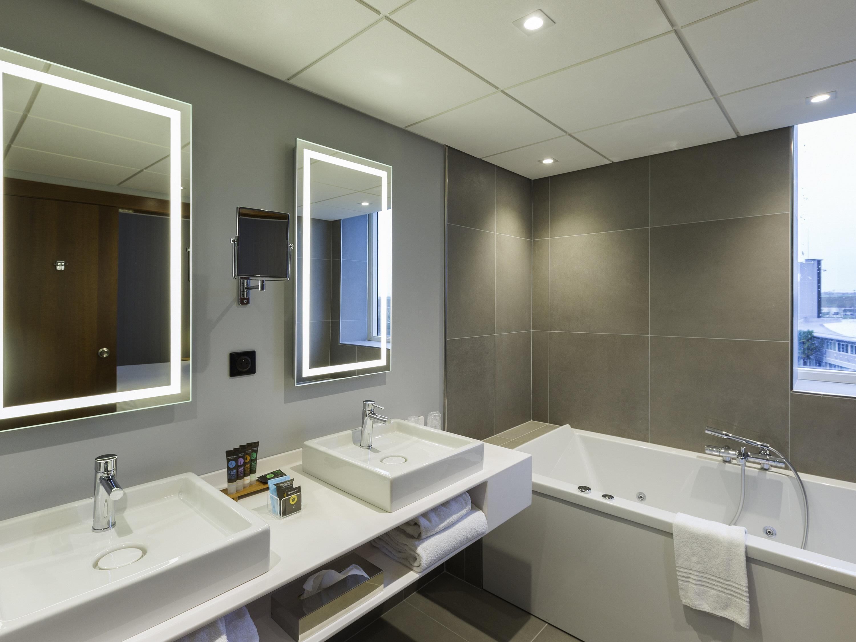 Ein modernes Badezimmer mit zwei Waschbecken, einem großen Spiegel und einer Badewanne.