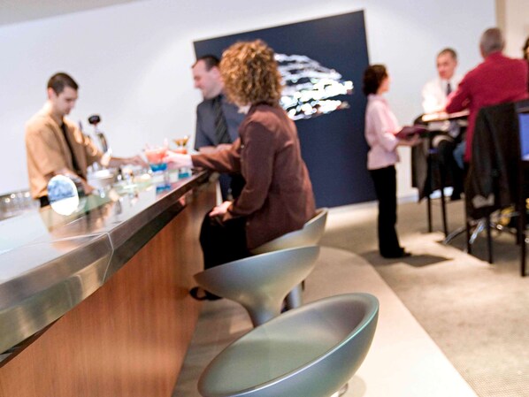 Zona de bar moderna con mostrador y taburetes.