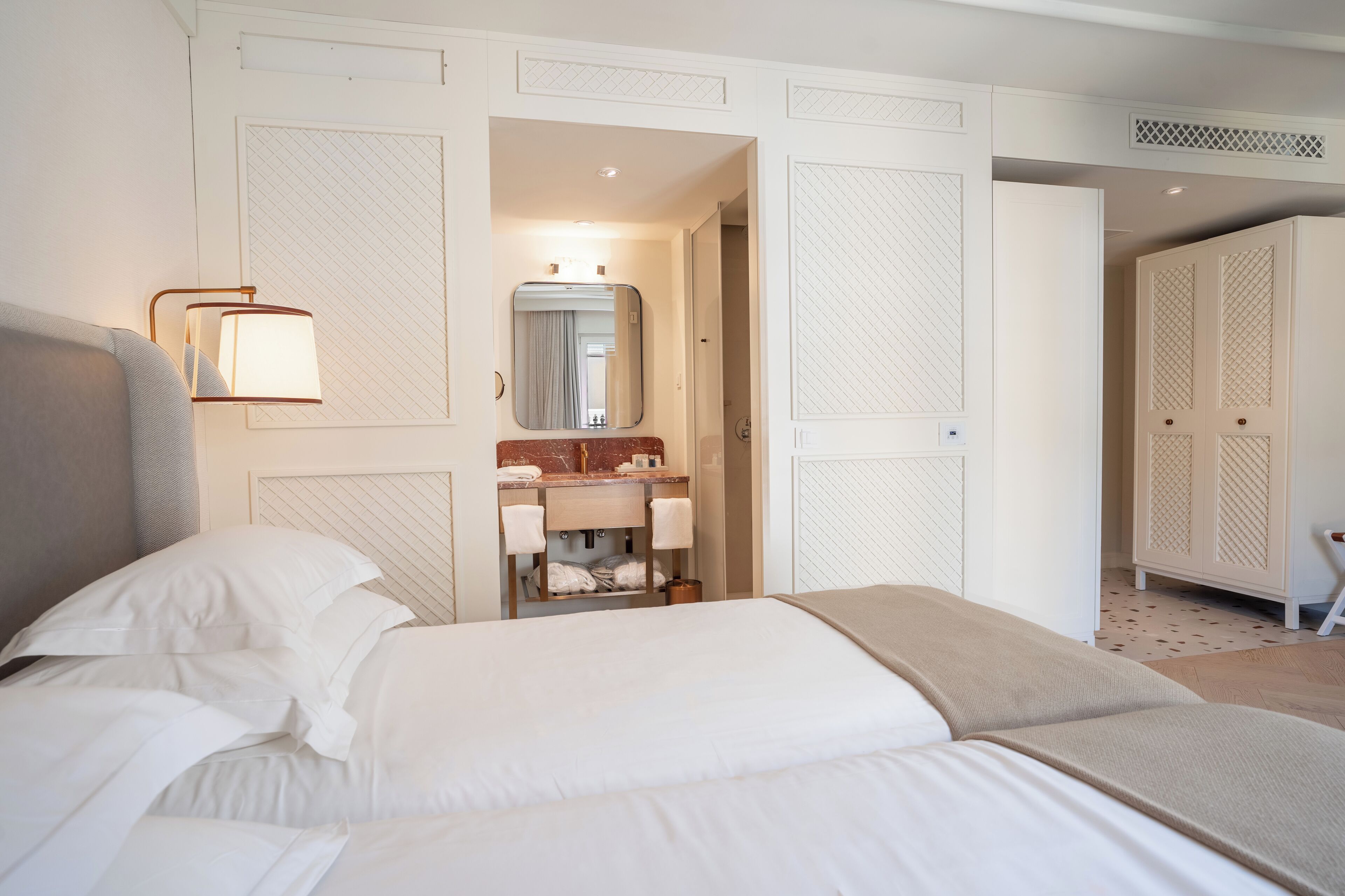Ein Hotelzimmer mit einem großen Bett, einem Nachttisch, einem Spiegel und einem Kleiderschrank.