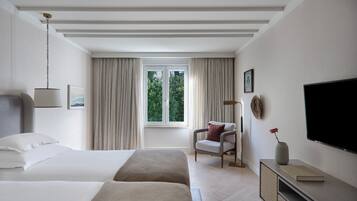 A hotel room with a bed, a chair, a TV, and a window with curtains.