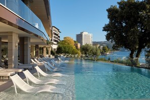 Un espace piscine avec des chaises longues et vue sur la mer.