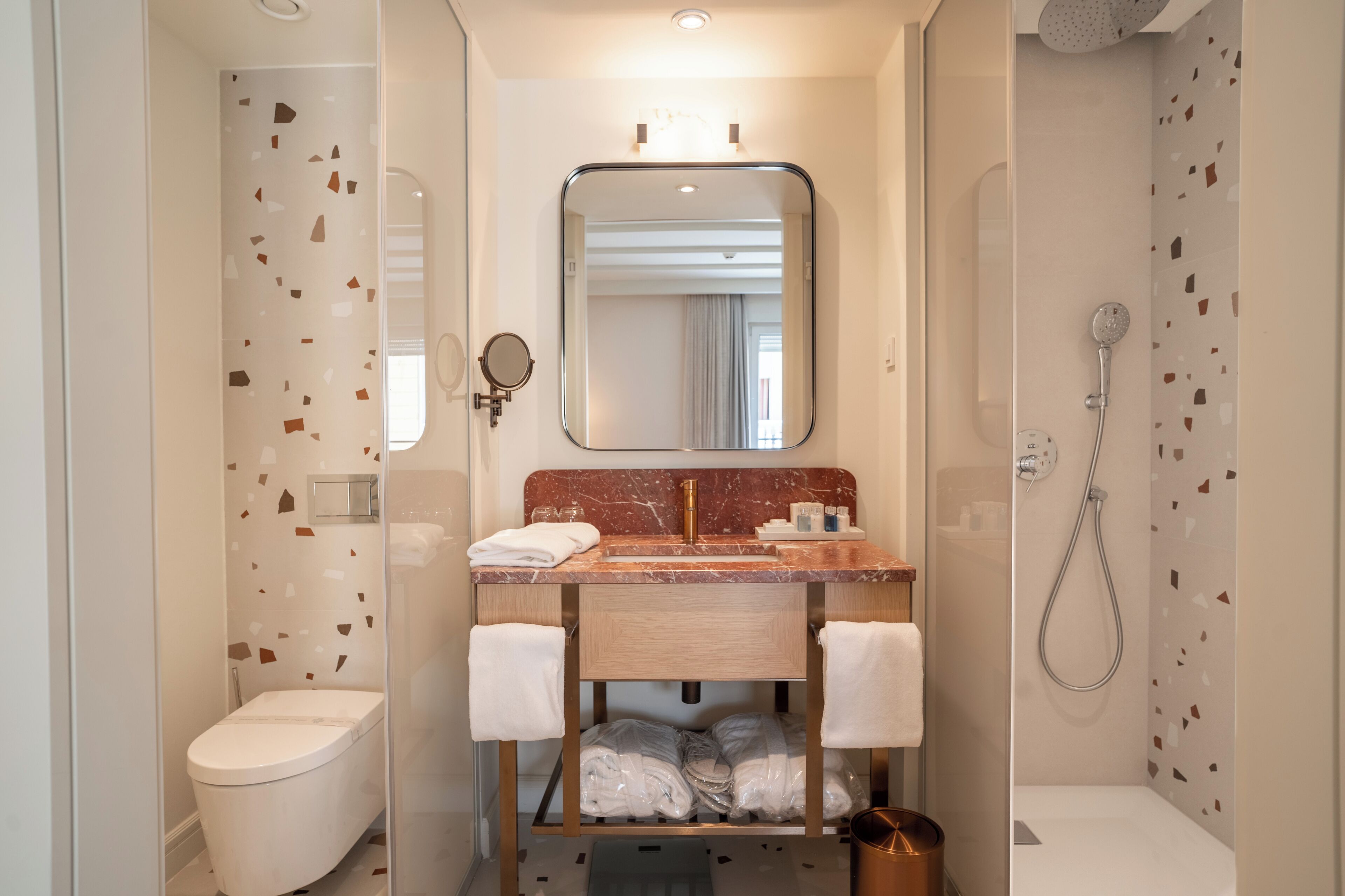 Une salle de bain moderne avec un lavabo en marbre, un grand miroir, des toilettes et une douche.