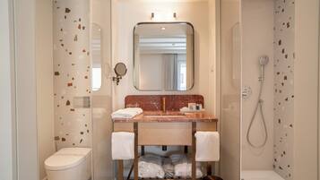 Une salle de bain moderne avec un lavabo en marbre, un grand miroir, des toilettes et une douche.
