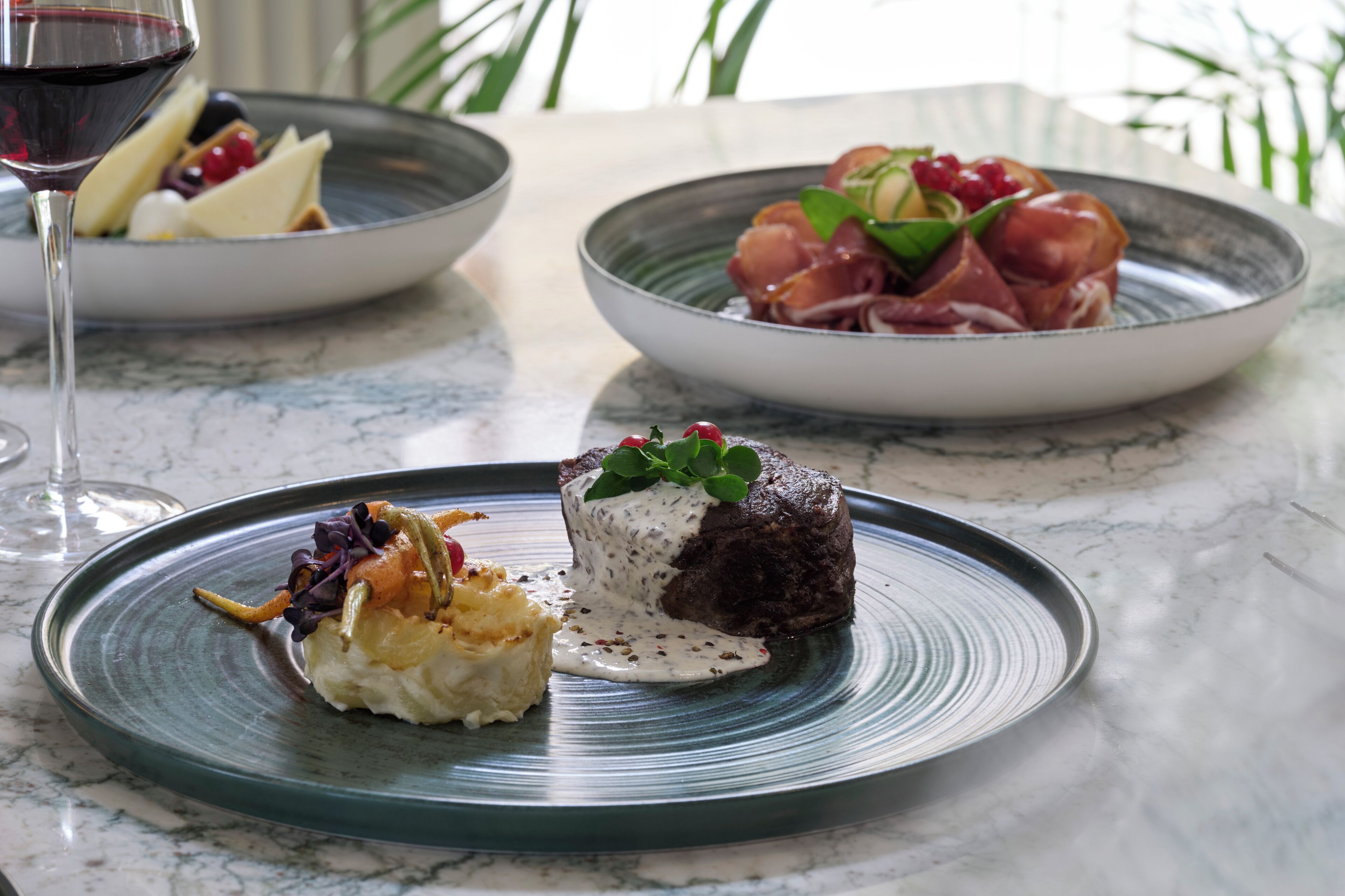 A marble table with three plates of food.