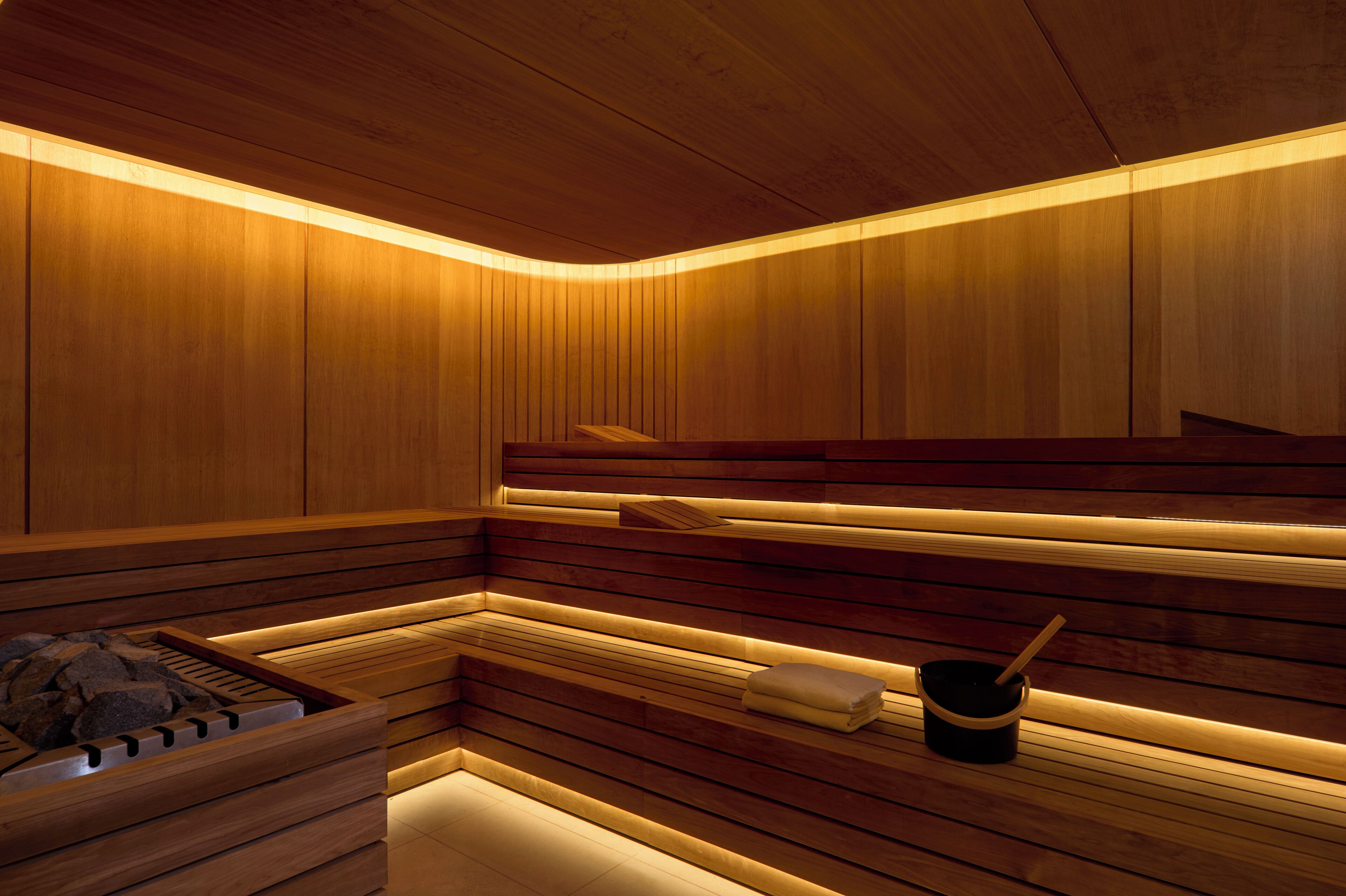 A sauna with wooden benches and a stone basin.