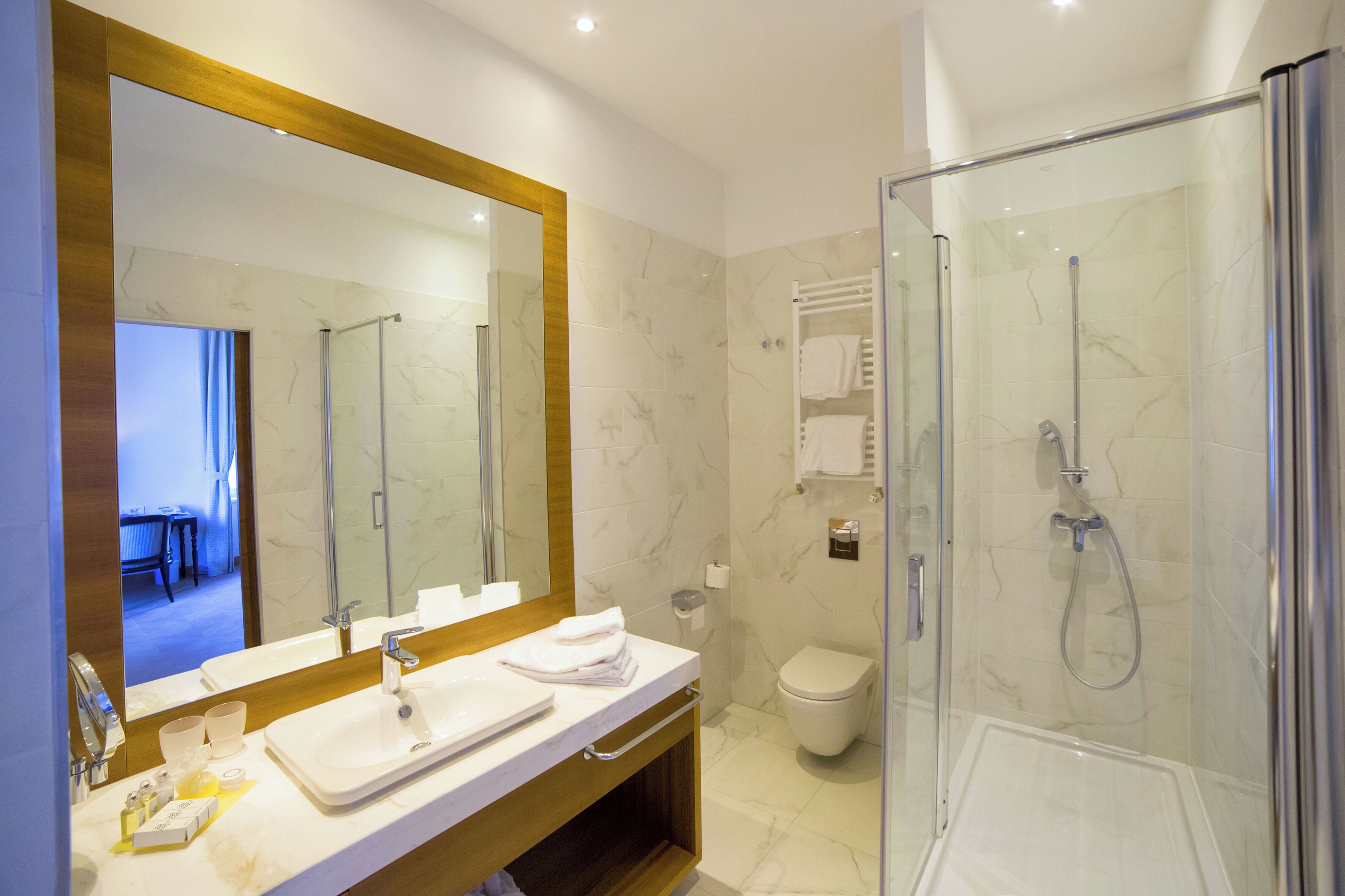 A modern bathroom with a glass-enclosed shower, a large mirror, and a white sink.