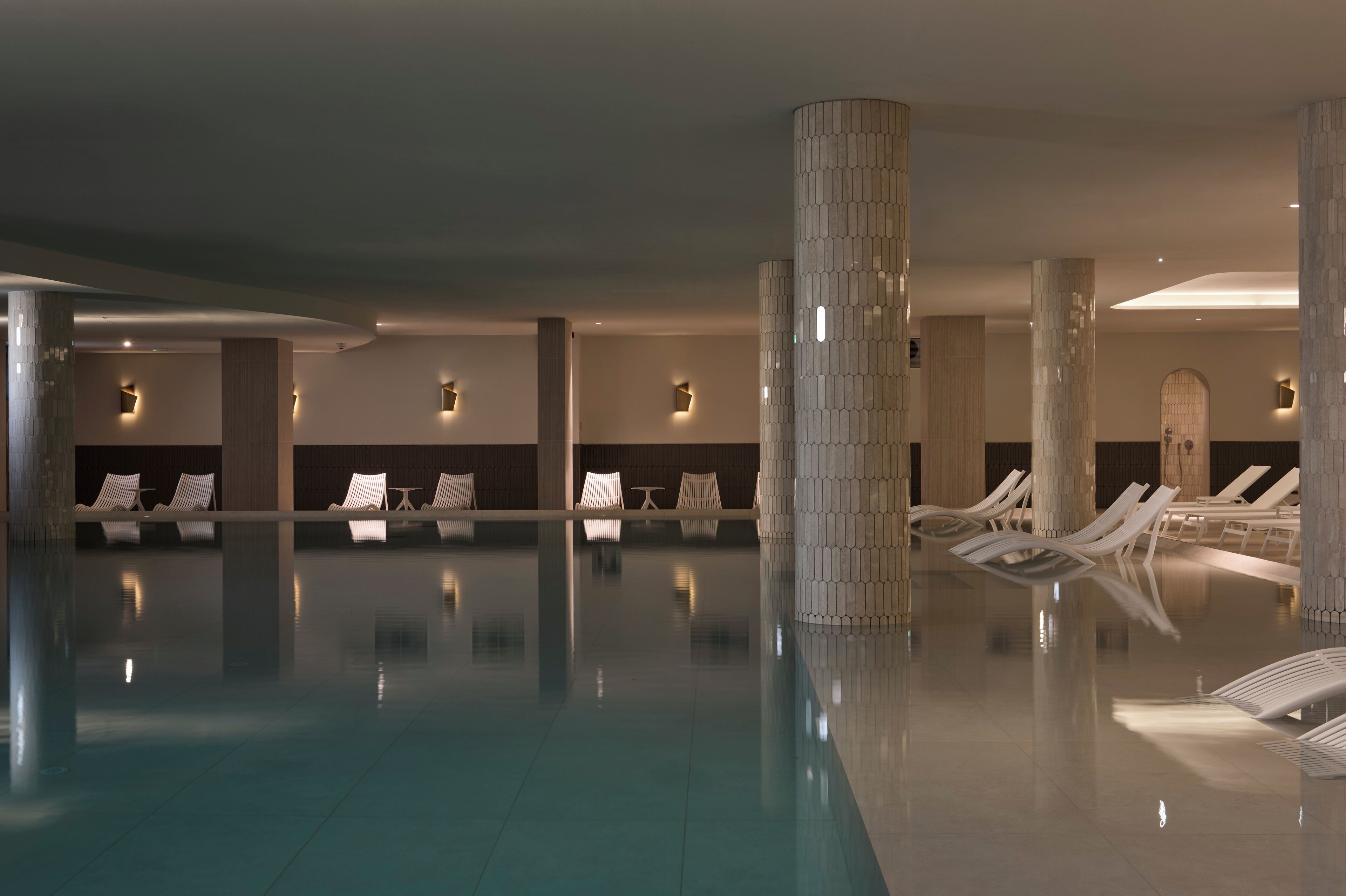 Una piscina techada, una piscina al aire libre, sombrillas