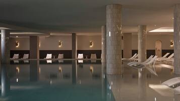 Una piscina techada, una piscina al aire libre, sombrillas