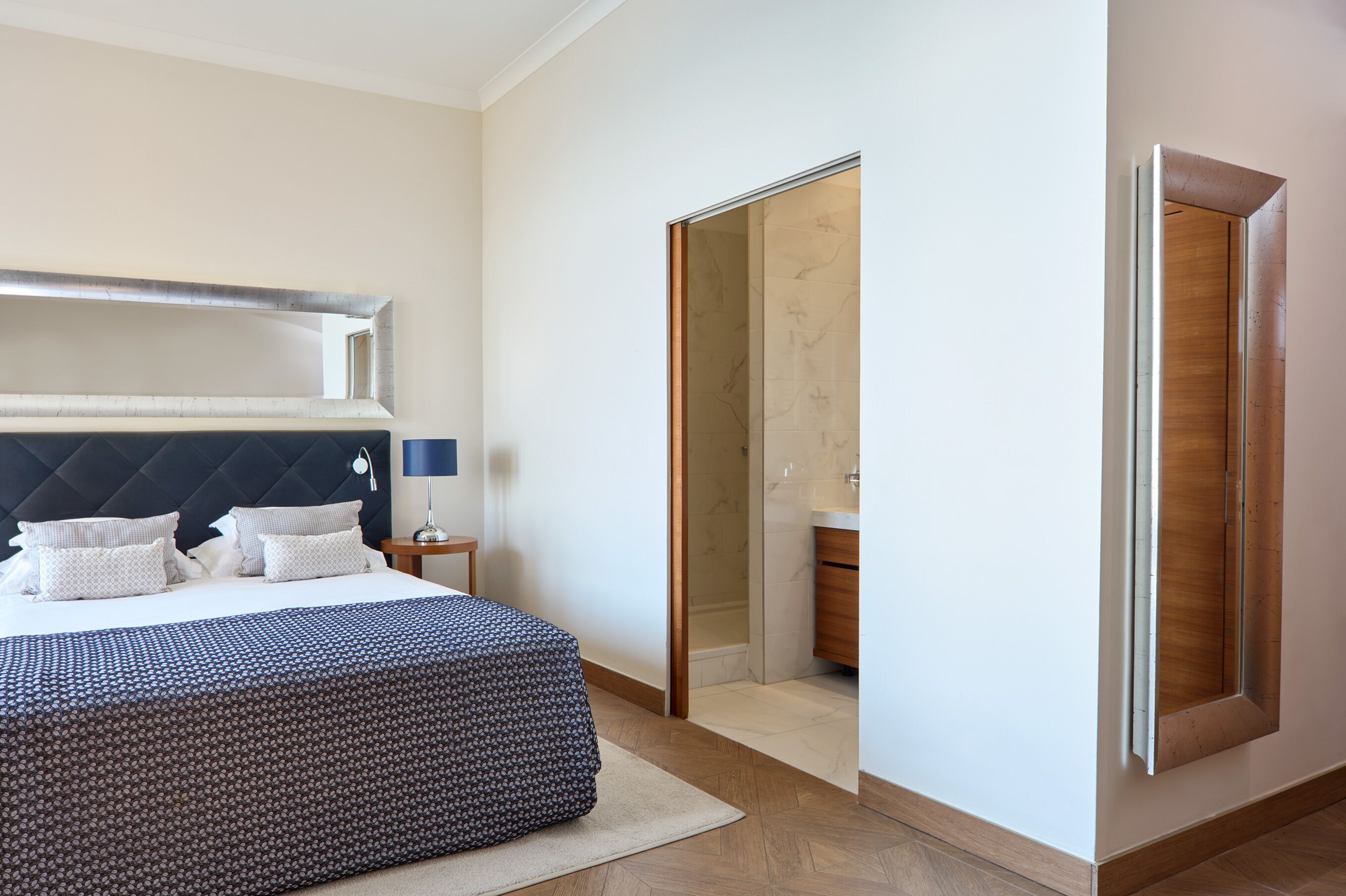Un dormitorio con cama, mesita de noche y espejo.