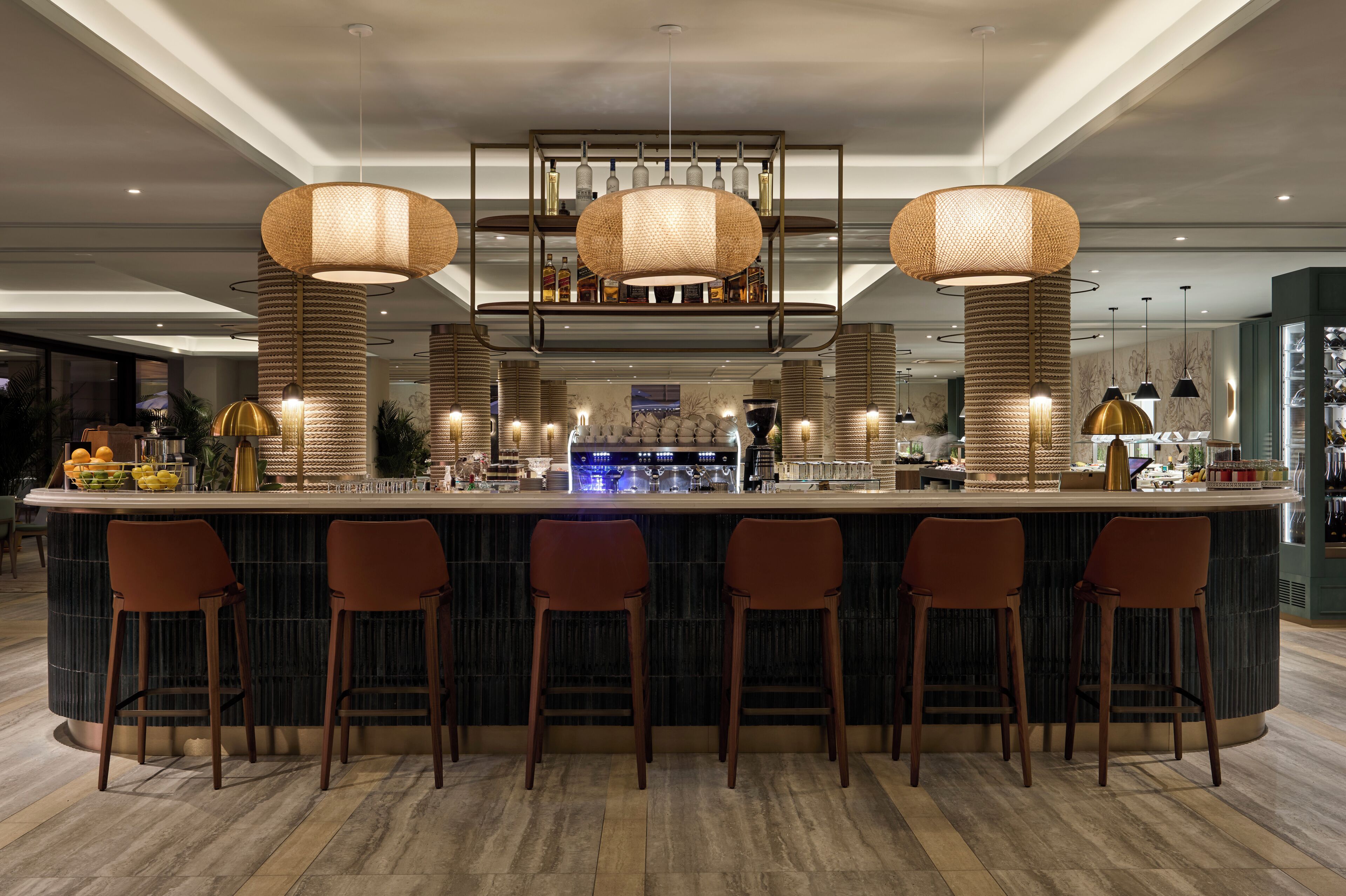 A bar area with a central island, bar stools, and hanging pendant lights.