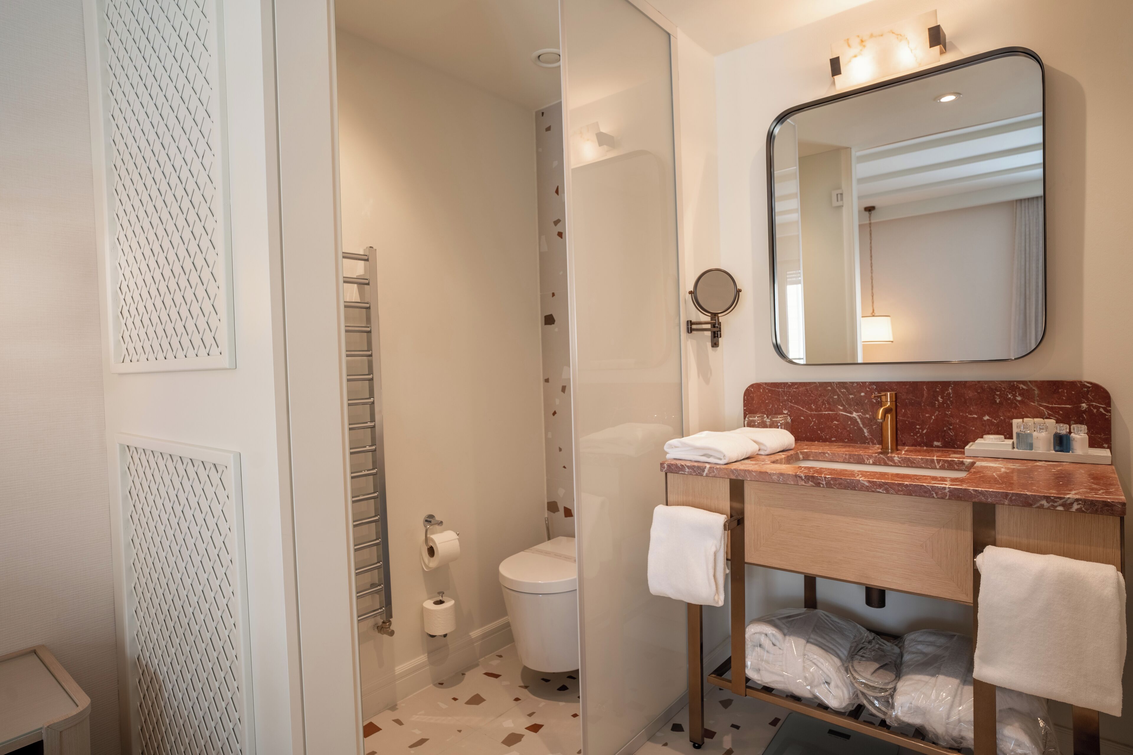 Un bagno moderno con cabina doccia in vetro, lavabo in marmo e specchio sopra.