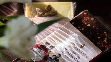 A cup of coffee on a saucer with a spoon, a chocolate bar, and a chocolate wrapper on a table.