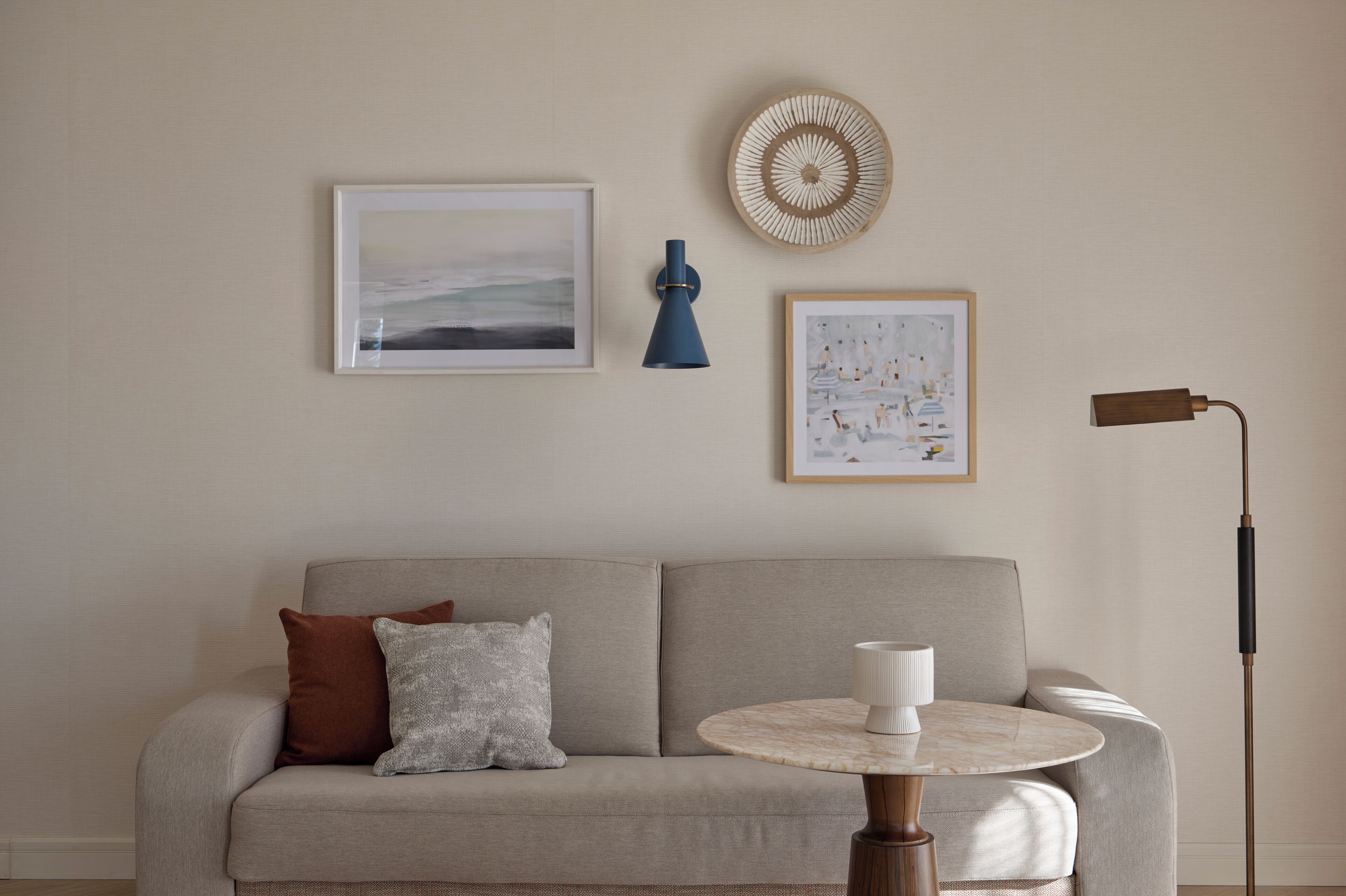 A living room with a sofa, a round table, and two wall-mounted lamps.