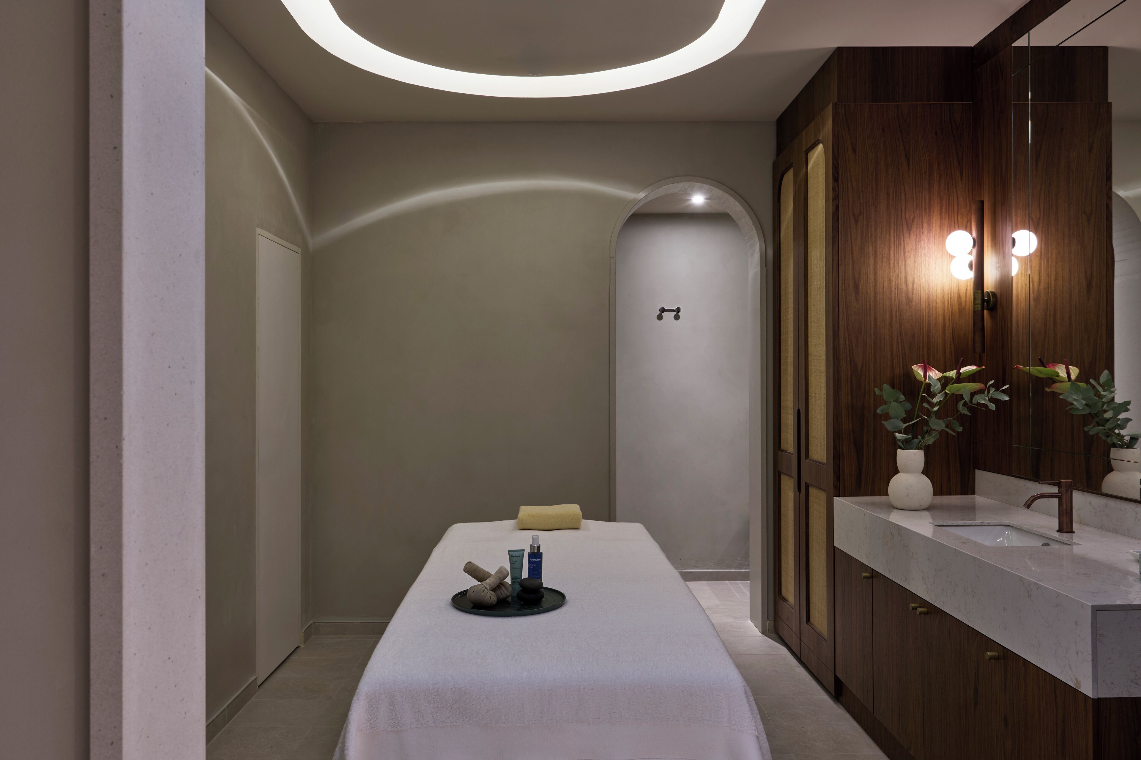 Uma sala de spa moderna com mesa de massagem, pia e espelho.