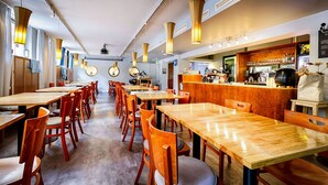 A restaurant with wooden tables and chairs, a bar area, and pendant lighting. - Eurohostel (Helsinki)