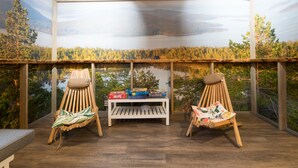 A wooden deck with two wooden chairs and a small table, overlooking a forested lake. - Eurohostel (Helsinki)