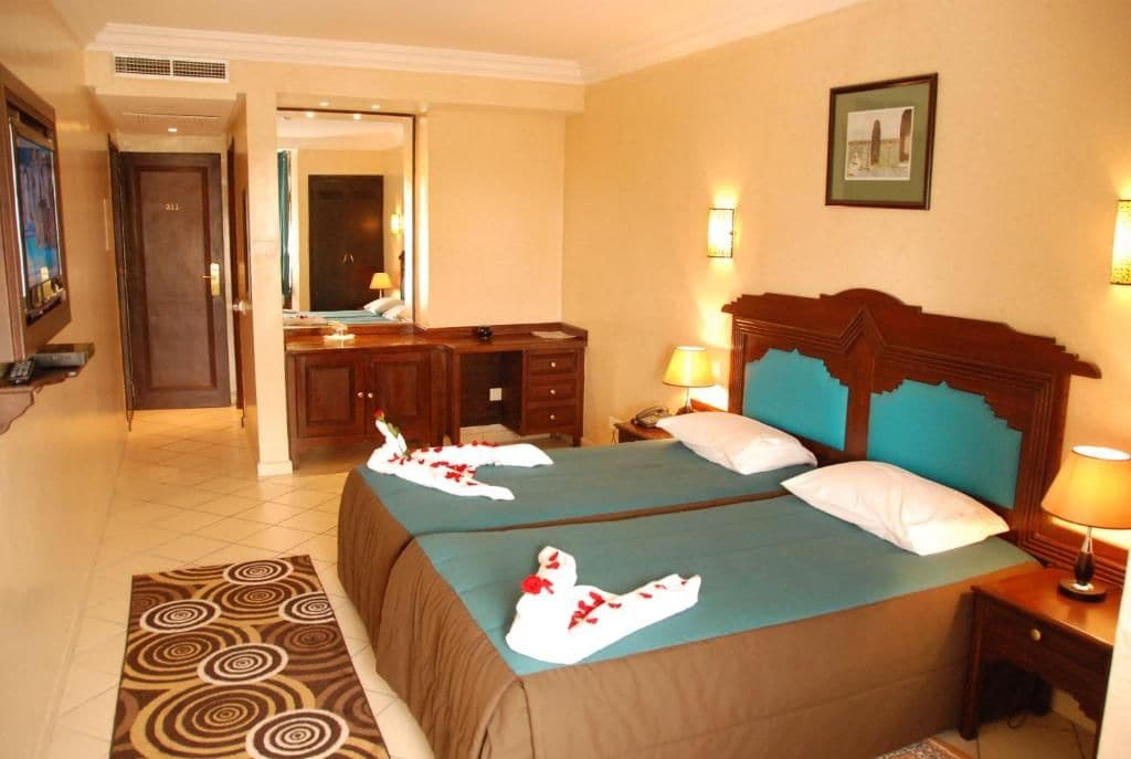 Habitación de hotel con dos camas, un baño y un pasillo.