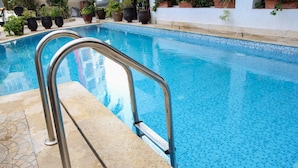Una piscina con barandillas metálicas y plantas en macetas a lo largo del borde.