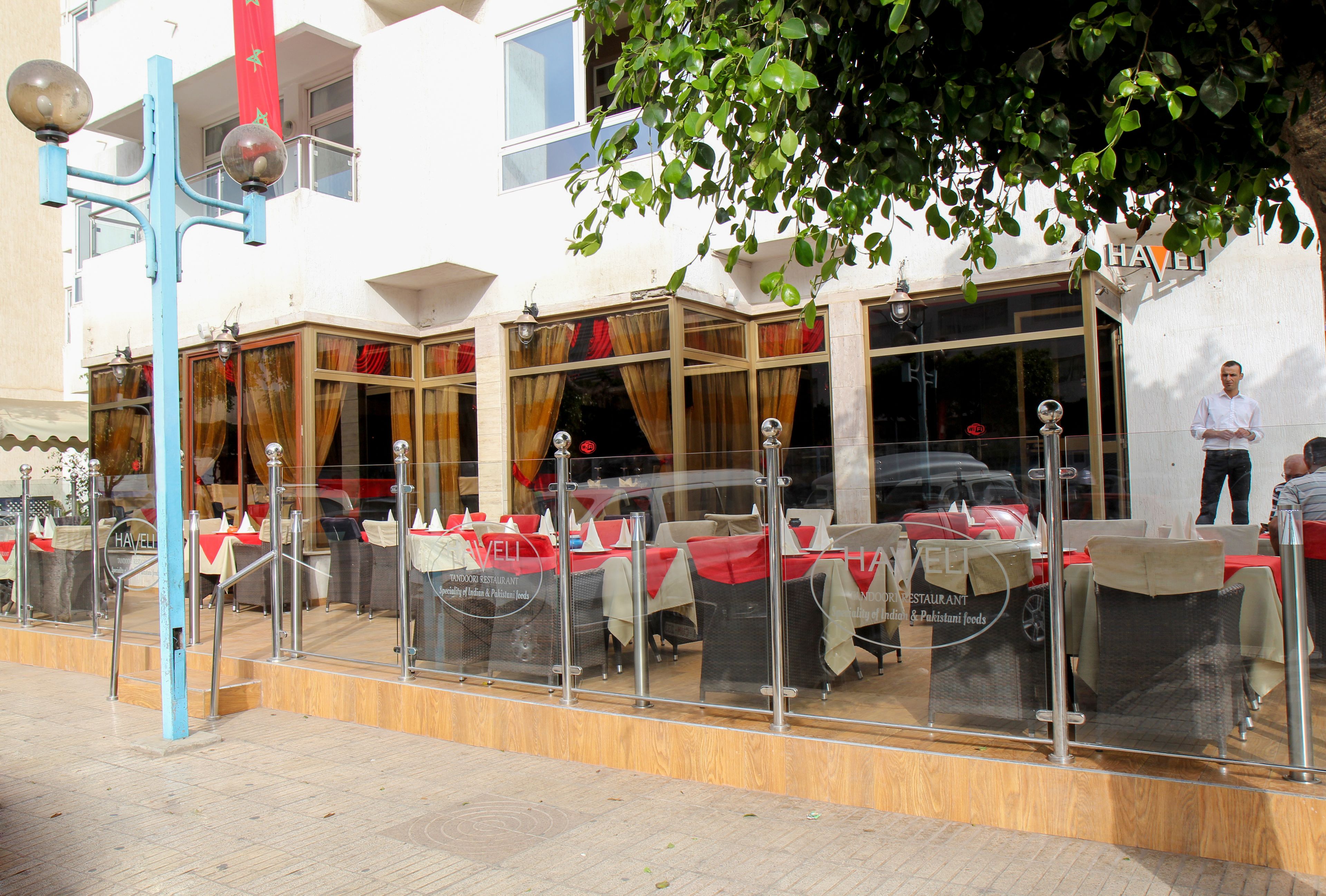 A restaurant with outdoor seating, glass barriers, and a flag.