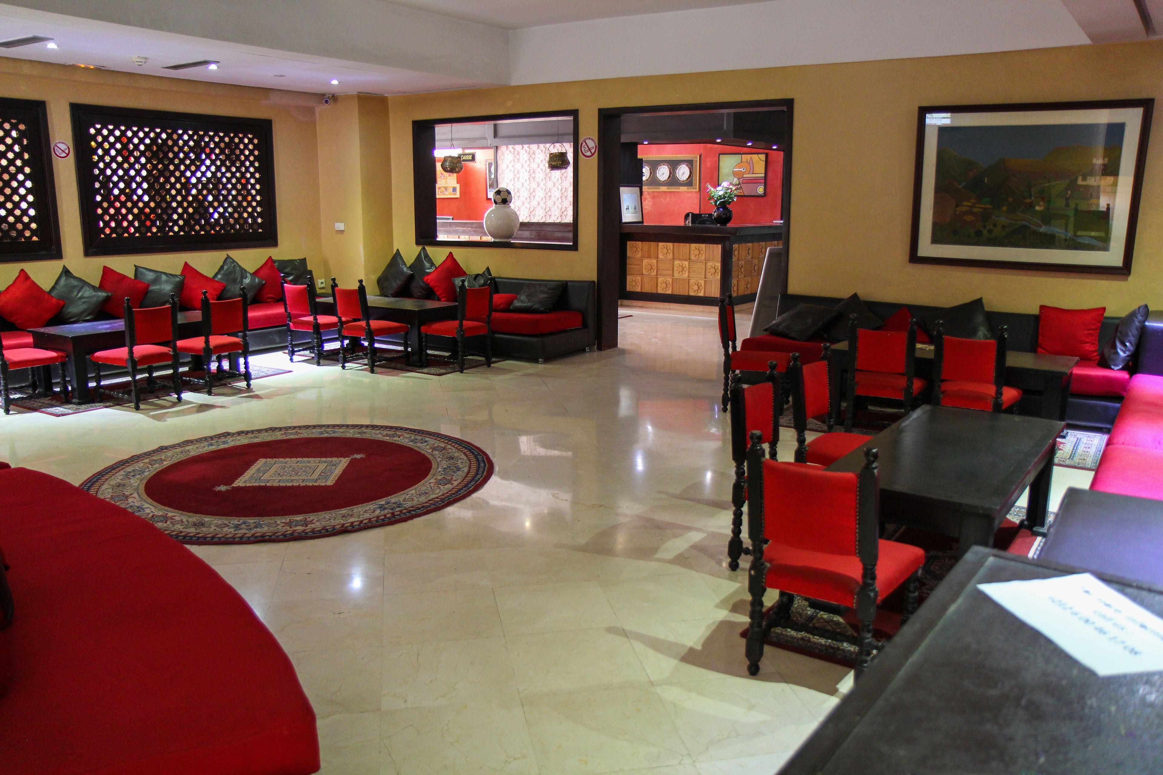 A hotel lobby with red and black seating, a reception desk, and a large framed picture on the wall.